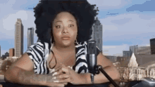 a woman is sitting in front of a microphone in front of a city skyline .