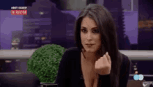 a woman is giving the middle finger while sitting in front of a television .