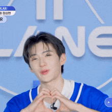 a young man in a blue shirt making a heart shape