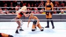 a woman is kneeling down in a wrestling ring while another woman stands behind her .