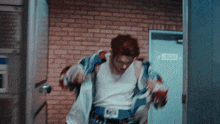 a man with red hair is standing in front of a brick wall and a door that says escape