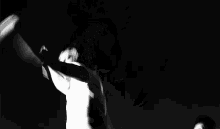 a black and white photo of a woman dancing in the dark .