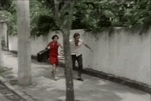 a man and woman are running down a sidewalk holding hands