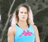a woman wearing a blue kappa tank top looks serious