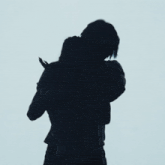 a man and a woman are squatting down in front of a white wall