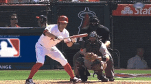 a baseball player getting ready to hit a ball in front of a banner that says angels
