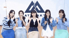 a group of girls are posing for a picture in front of a logo that says " akt "