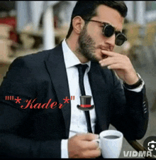 a man in a suit holds a cup of coffee and a top hat