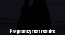 a person in a black dress is standing in front of a sign that says " pregnancy test results "
