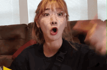a woman wearing glasses and a black shirt has her mouth open