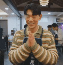 a man wearing a striped sweater and an apron with a foreign language on it