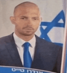 a man in a suit and tie is standing in front of a flag .