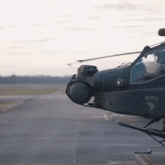 a military helicopter is sitting on a runway with the army logo on the side .