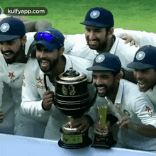 a group of men are posing for a picture with a trophy