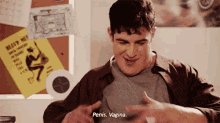 a man is sitting at a desk with his hands on his chest and says penis . vagina .