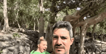 a man and a woman are standing in the woods .