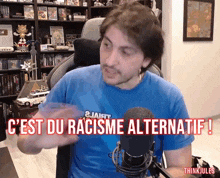 a man in a blue shirt is talking into a microphone with the words " c'est du racisme alternatif " on the bottom