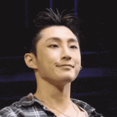 a close up of a man wearing a plaid shirt and necklace .