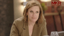 a woman is sitting in front of a mkr sign