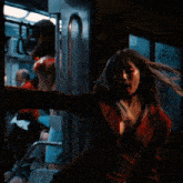 a woman in a red jacket is standing on a train