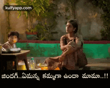 a woman is sitting on the ground next to a child and a table .