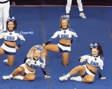 a group of cheerleaders with cali on their uniforms are performing on a blue mat .