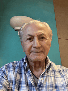 a man wearing a plaid shirt looks at the camera