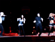 a group of people singing and dancing on a stage in front of a mirror