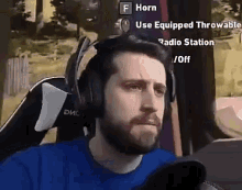 a man wearing headphones and a blue shirt is sitting in front of a computer screen .