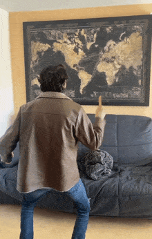 a man in a brown leather jacket is pointing at a map of the world