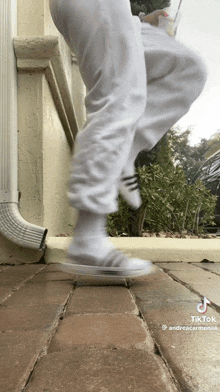 a person wearing white sweatpants and socks is jumping in the air .