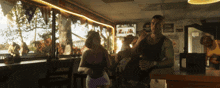 a man and a woman are dancing in a bar with a sign that says ' beer '