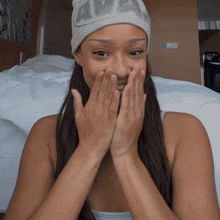 a woman wearing a nike beanie covering her face with her hands