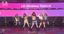 a group of girls are dancing on a stage in front of an lg ultragear festival banner