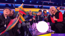 a group of people are sitting around a table with lithuanian flags