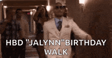 a man in a suit and tie is walking down a hallway with a group of people .