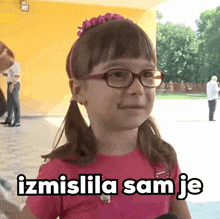 a little girl wearing glasses and a pink shirt with the words izmislila sam je