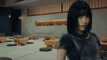 a woman in a black shirt is standing in a room with tables and chairs