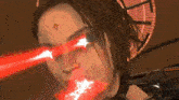 a close up of a woman 's face with a tattoo on her forehead and red lights coming out of her eyes