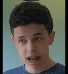 a young boy wearing a blue shirt is making a funny face with his mouth open .