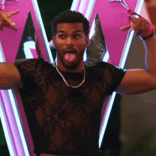 a man wearing a black lace crop top is sticking his tongue out .