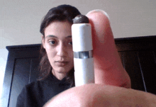 a woman in a black shirt is holding a small white object in her hand