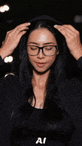 a woman wearing glasses crosses her arms and the word ai is on the bottom