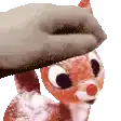 a person is petting a stuffed reindeer with a glove on its head .