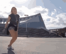 a woman is dancing in front of a building that says ' a ' on the front