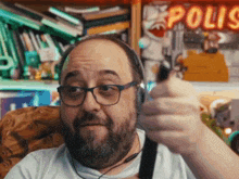 a man wearing glasses and headphones giving a thumbs up in front of a neon sign that says polis