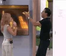 a man and woman are standing next to each other in front of a television .