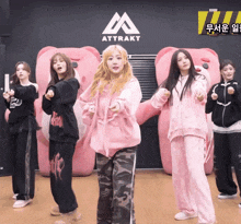 a group of girls are dancing in front of a sign that says " atttrakt "