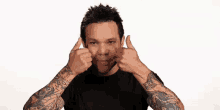 a man with tattoos on his arms is giving a thumbs up sign