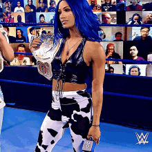 a woman in a cow print outfit holds a wrestling championship belt